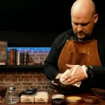 Le Shoe Shiner à l’atelier, en tablier de cuir, glaçant un soulier au chiffon