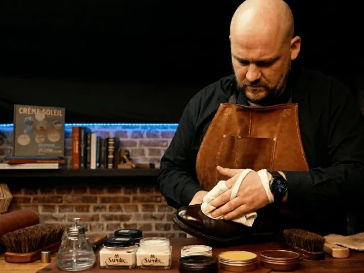 Le Shoe Shiner à l’atelier, en tablier de cuir, glaçant un soulier au chiffon